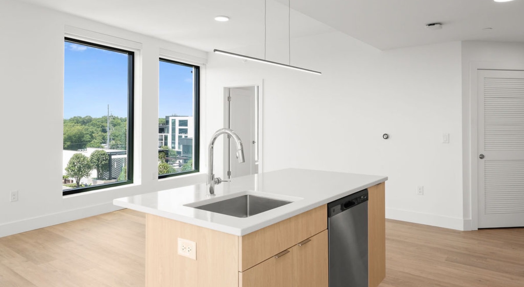 kitchen island with white countertops and living area with large windows