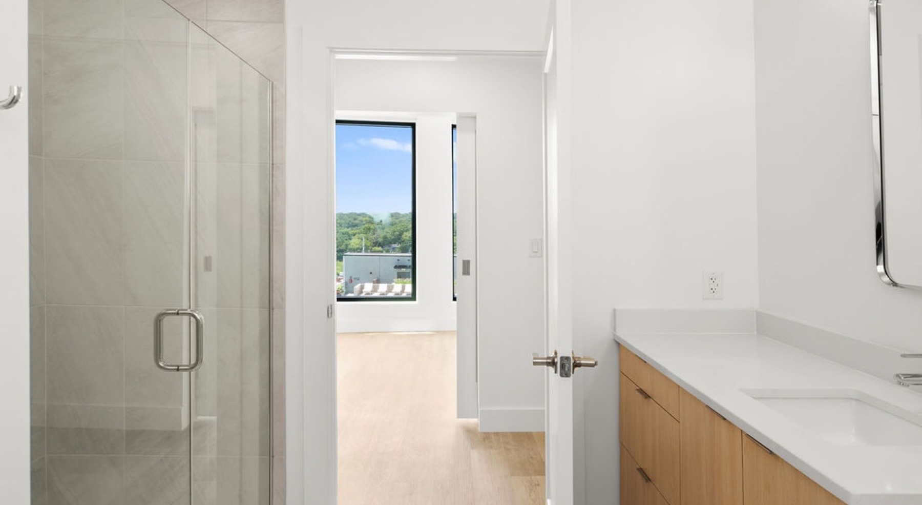 bathroom with a sink, mirror, glass shower and white countertops